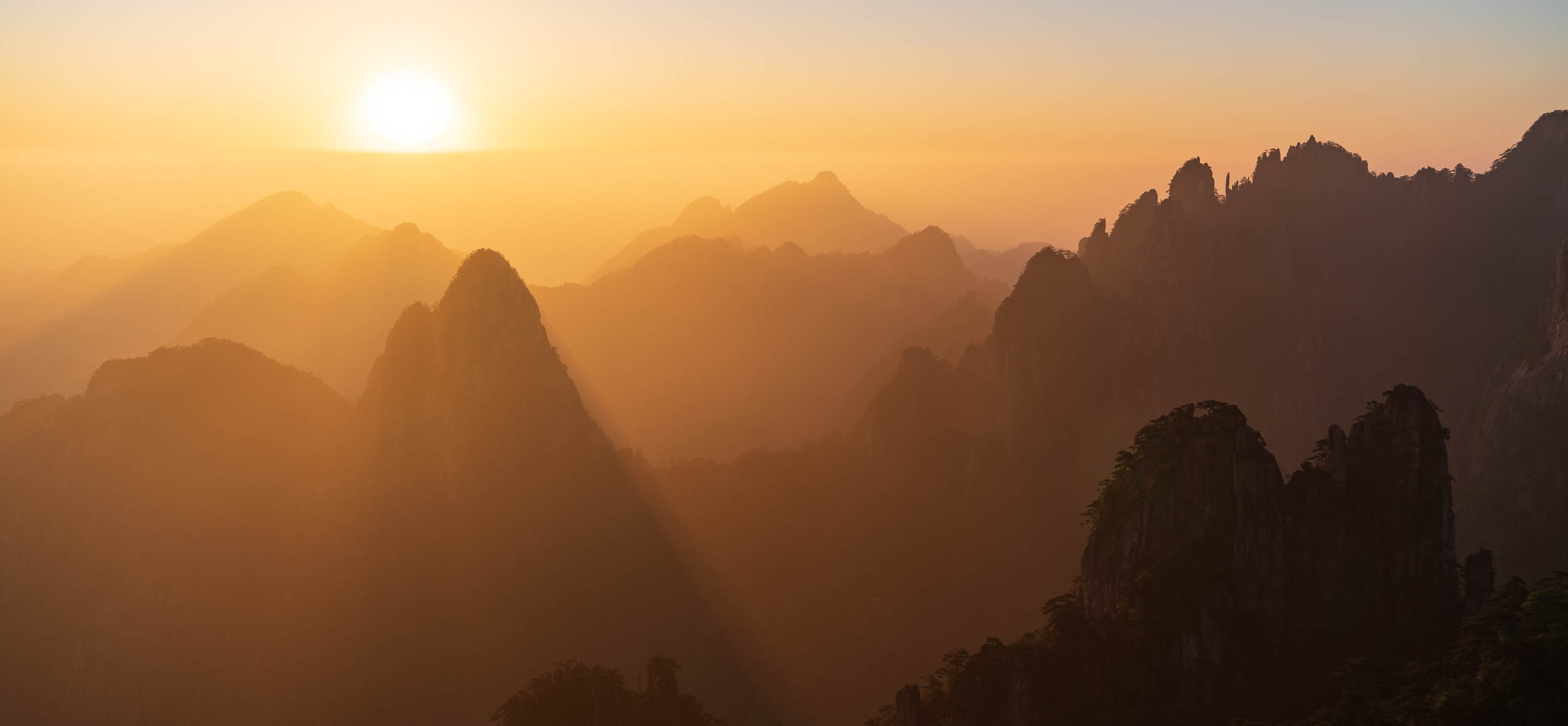 Huangshan peaks layered in golden sunrise mist